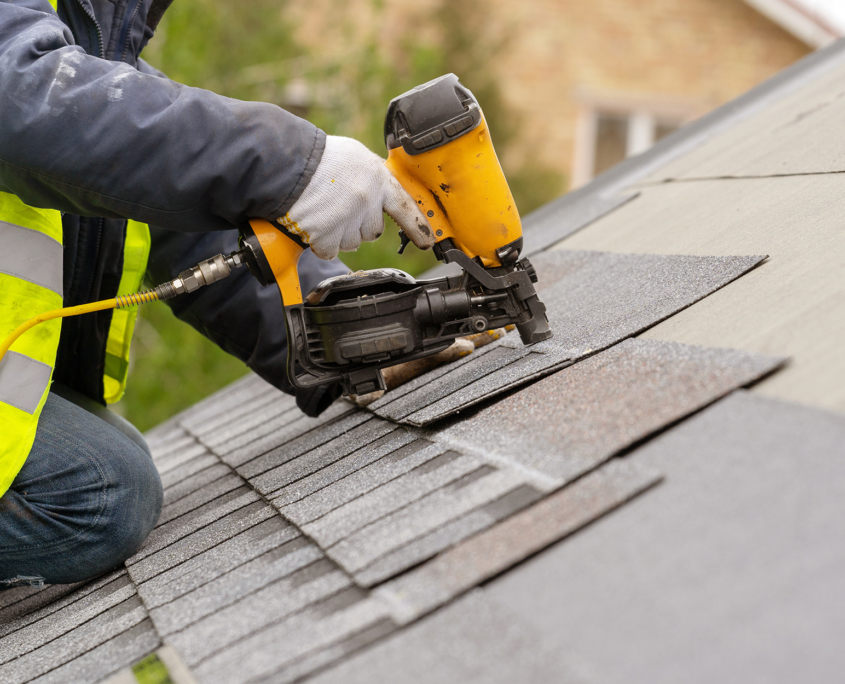 Person with Nail Gun Installing Roof Shingles