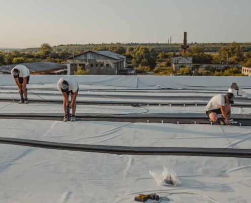 three workers on a commercial roof
