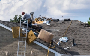 Worker on the roof of a 2-storey family house installing new asphalt shingles