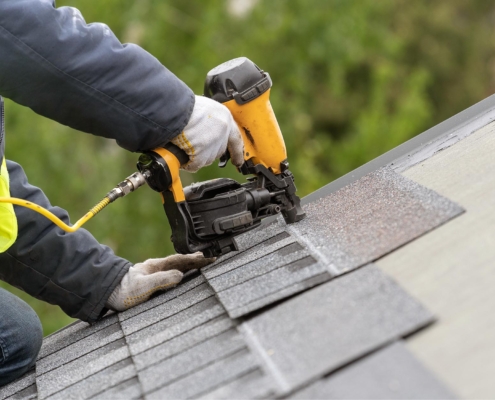 Image of a worker installing new tiles on a residential roof.