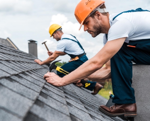 Image of two workers repairing a shingle roof.