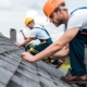 Image of two workers repairing a shingle roof.